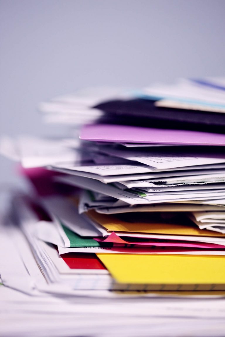 A close up view of the corner of a pile of books, papers, paperwork, bills and files in a jumble